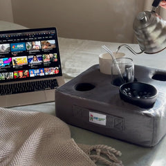 Cup Cozy Pillow in use on sofa holding two drinks and a phone for convenience