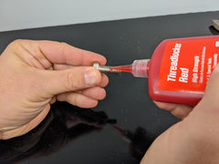 Permatex 27140 being applied to a bolt demonstrating secure fastening