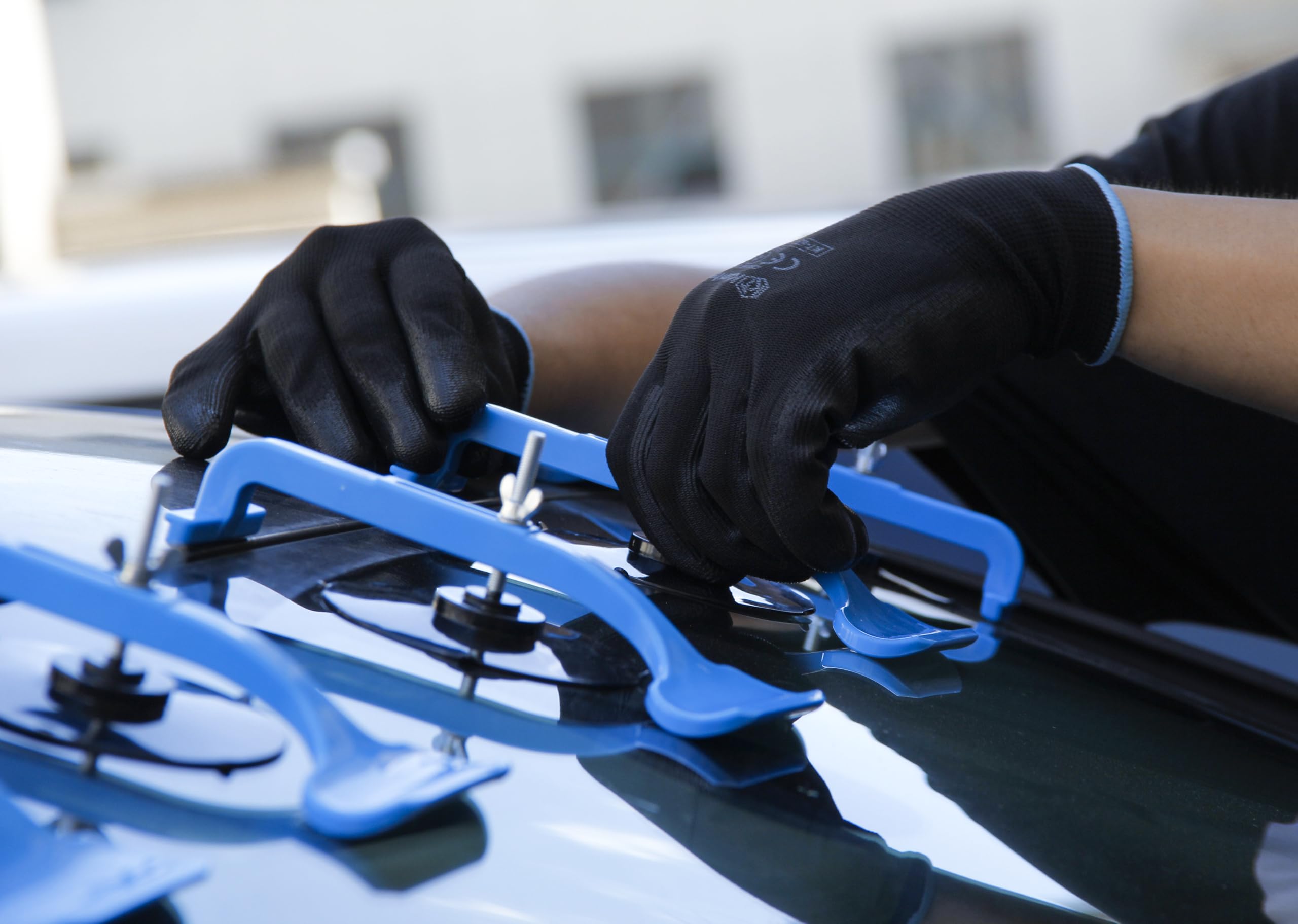 Akuttool clamp attached to windshield during repair showing stable positioning