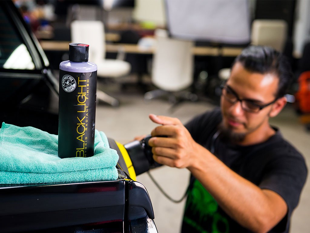 Chemical Guys product being applied to a black hood for visible shine