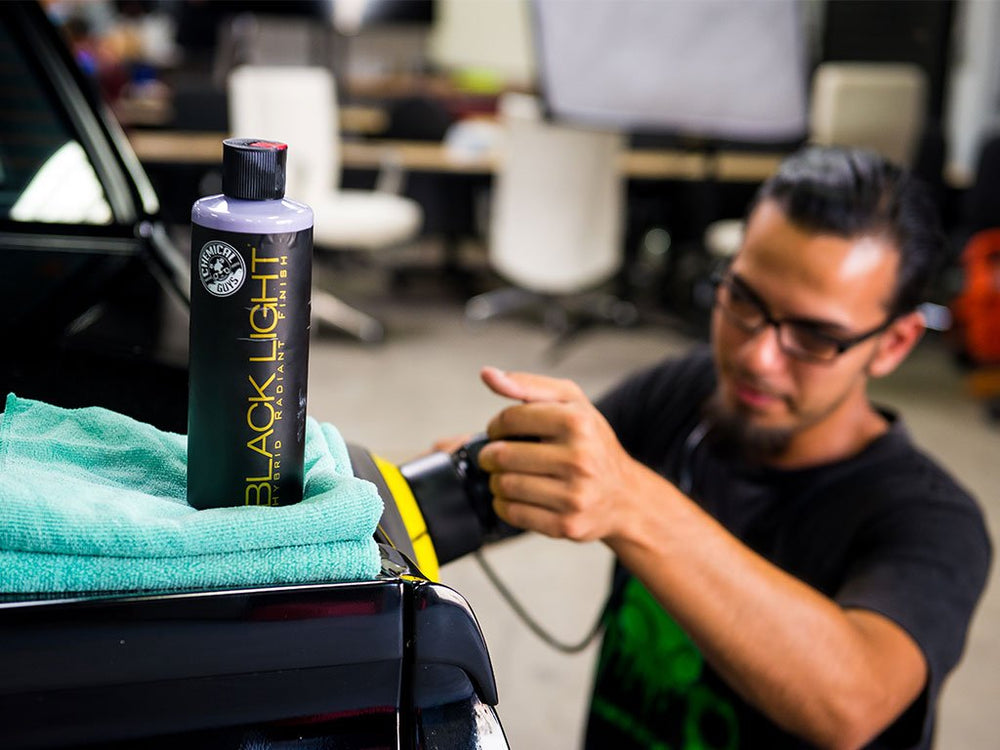 Chemical Guys product being applied to a black hood for visible shine
