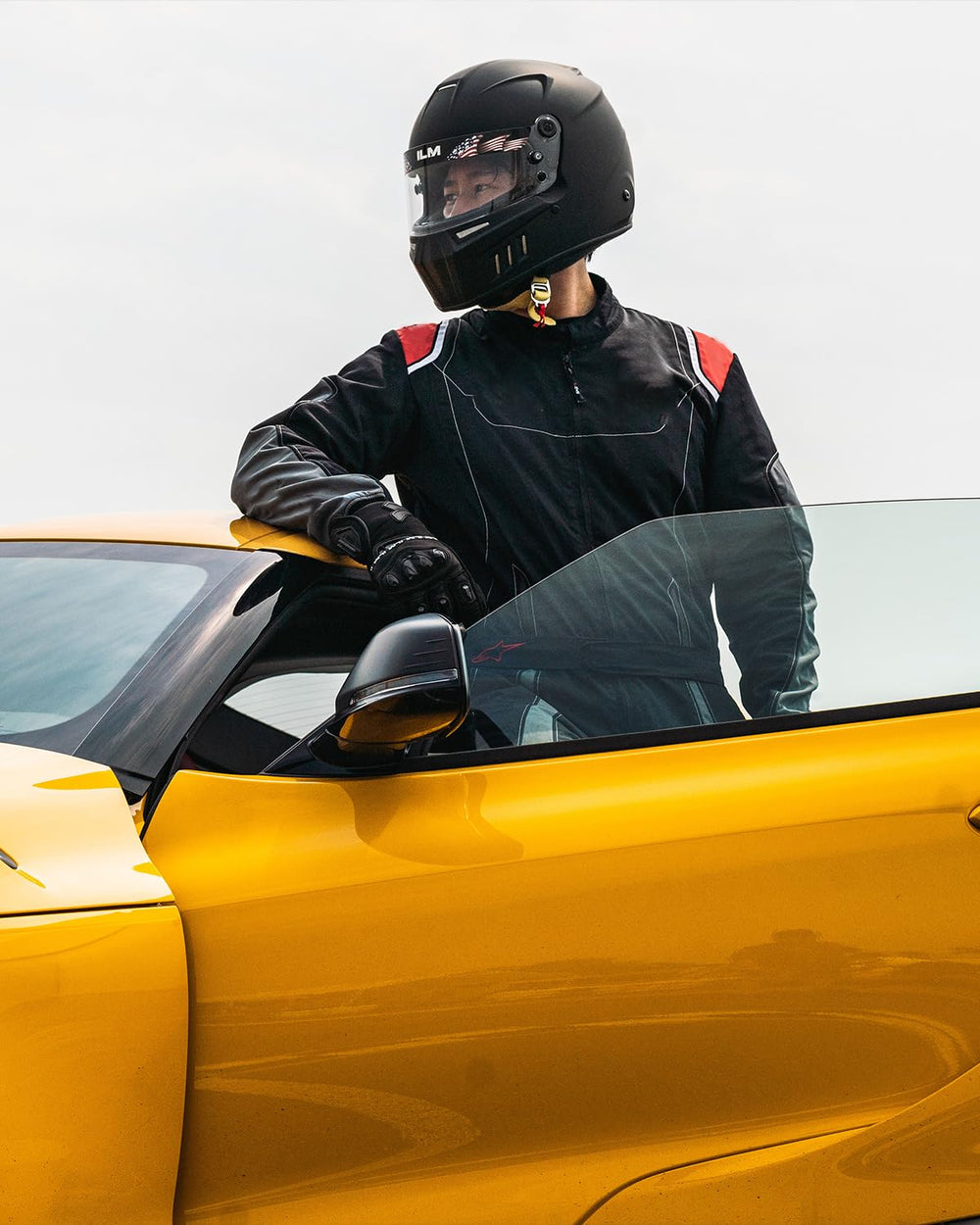ILM Snell helmet on race car seat lifestyle shot showing track-ready setup benefit