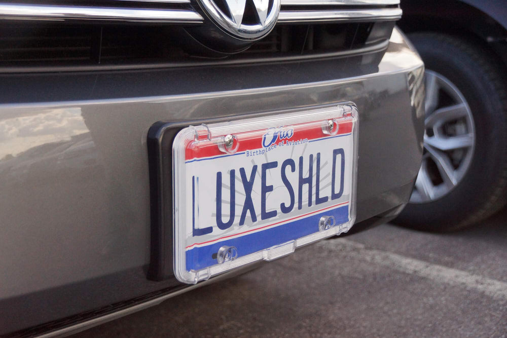 Luxe Shield lifestyle shot with car parked showing long-term plate preservation benefit