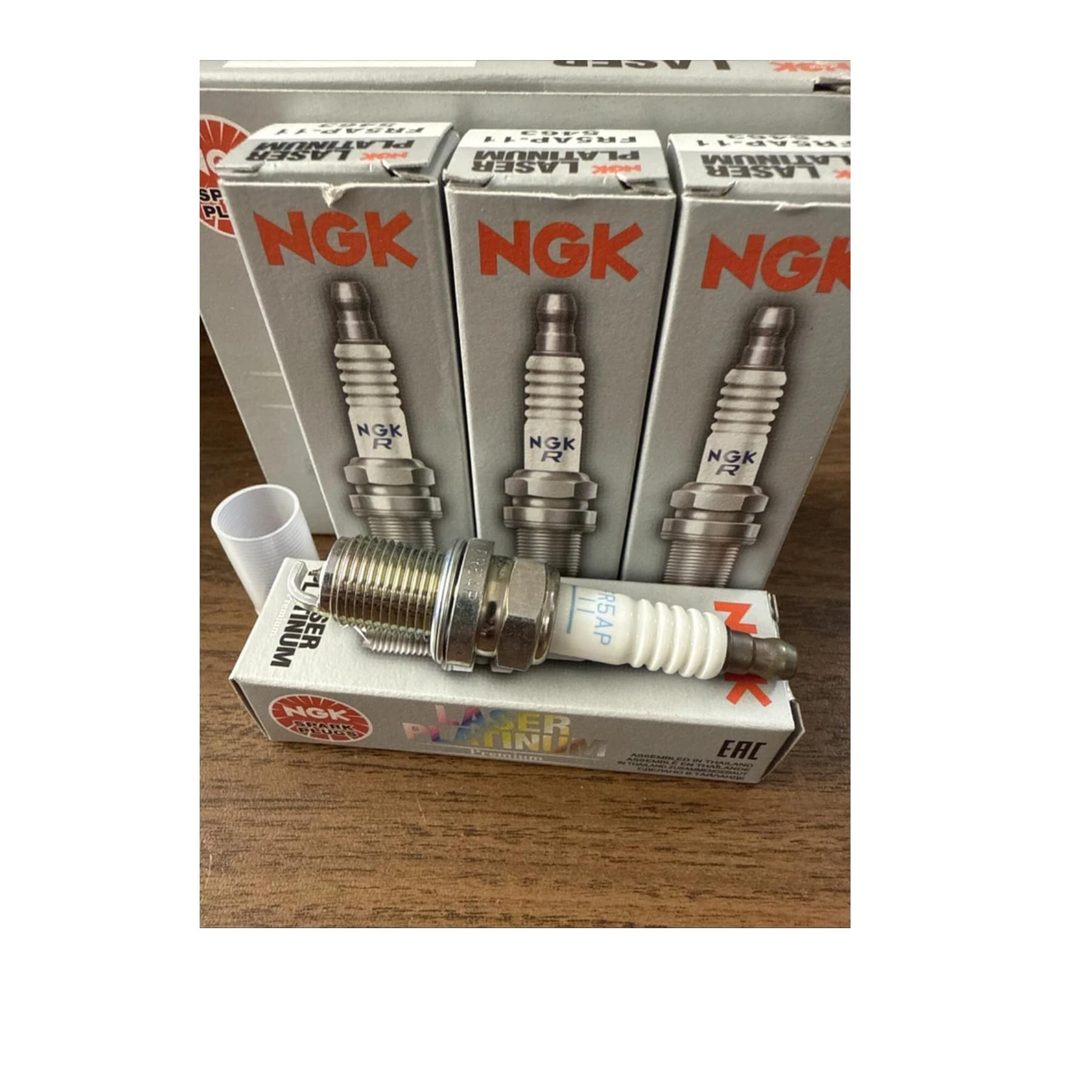 NGK spark plug next to ruler for scale showing reach and wrench diameter