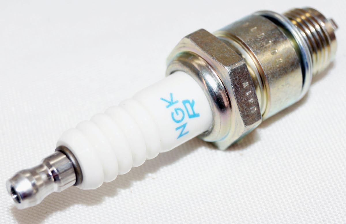 NGK spark plug next to coin for scale showing compact size and fitment clarity