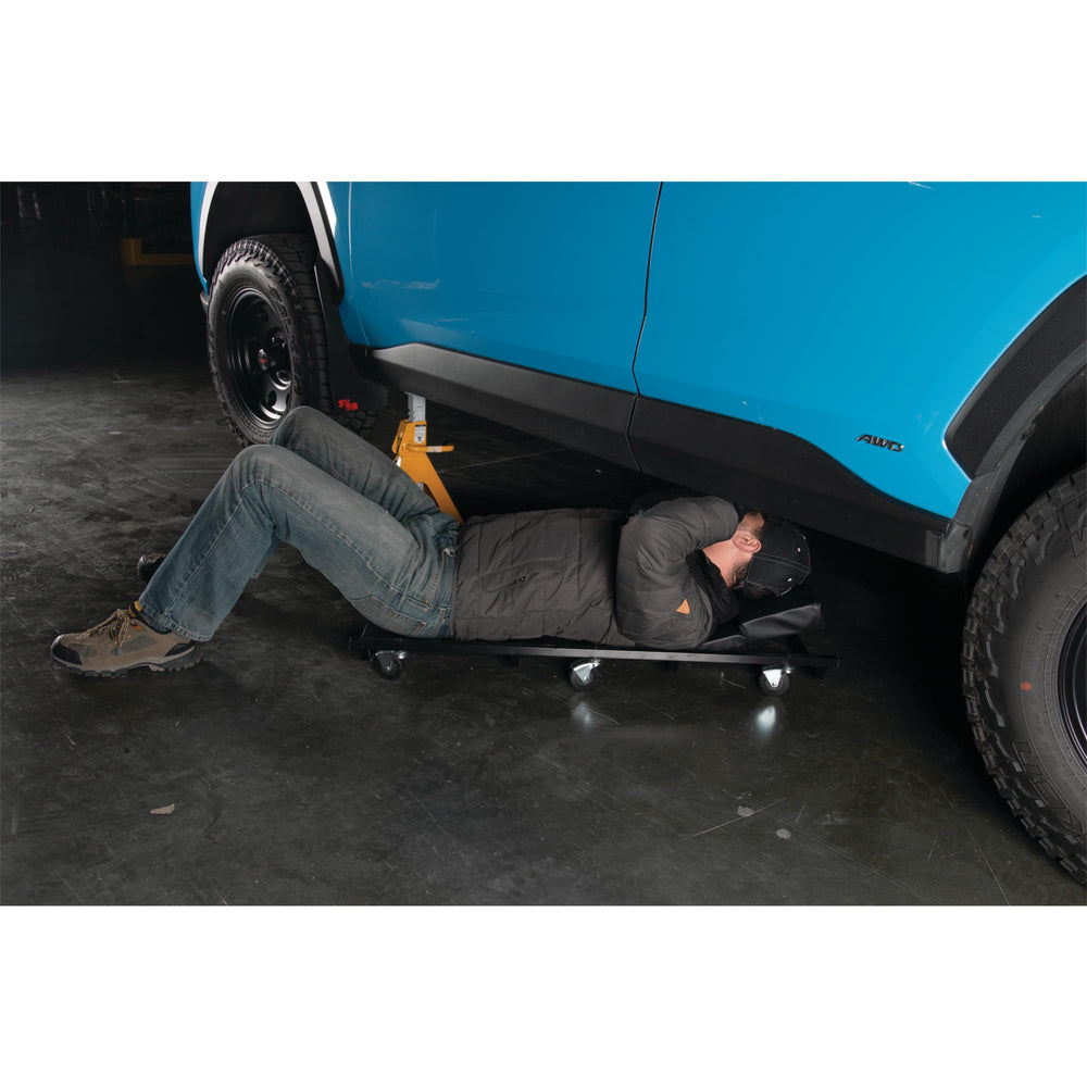 Performance Tool creeper next to tape measure for scale, clear size and fit benefit